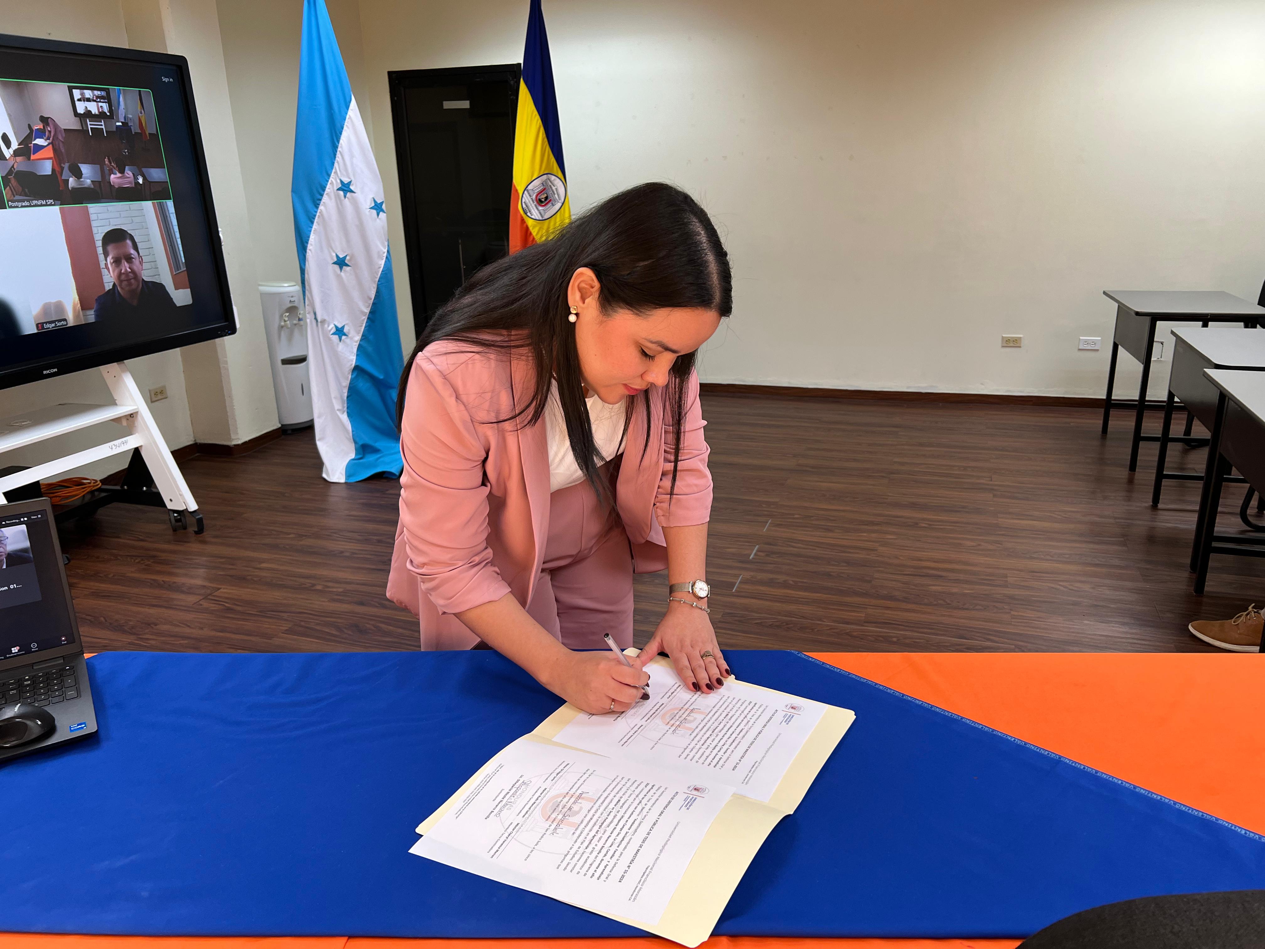 La Licda. Sthepanie Nicole Navarro Bonilla firmando el acta de defensa de tesis.